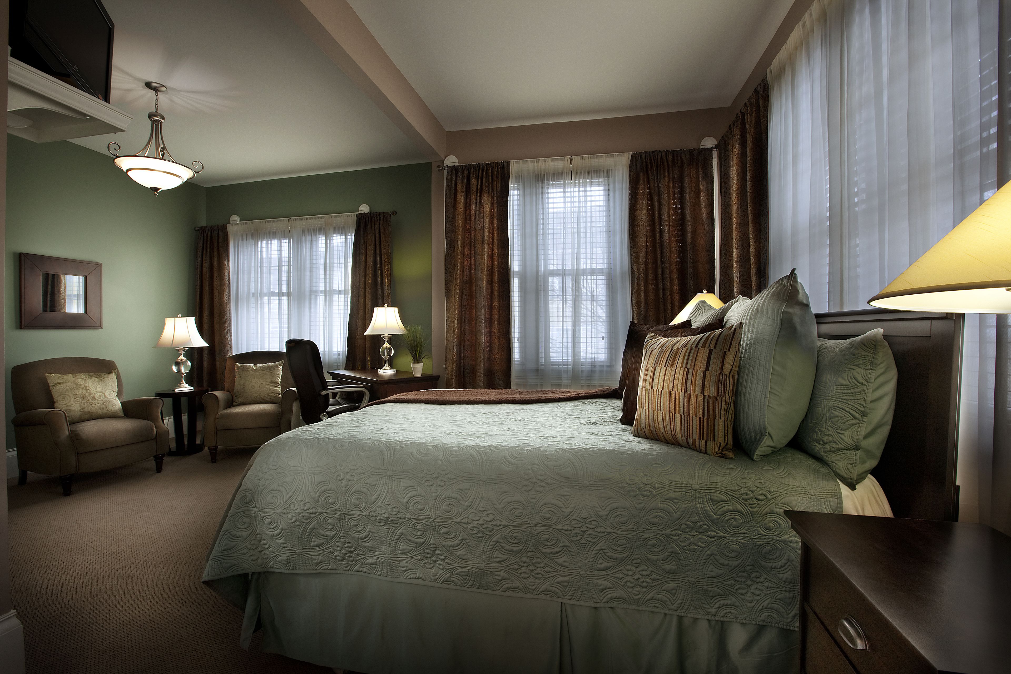 Una habitación de hotel con una cama grande, dos sillones, un escritorio y una lámpara.