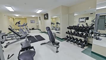 Uma academia com diversos equipamentos de exercício, incluindo esteiras, aparelhos de musculação e halteres.