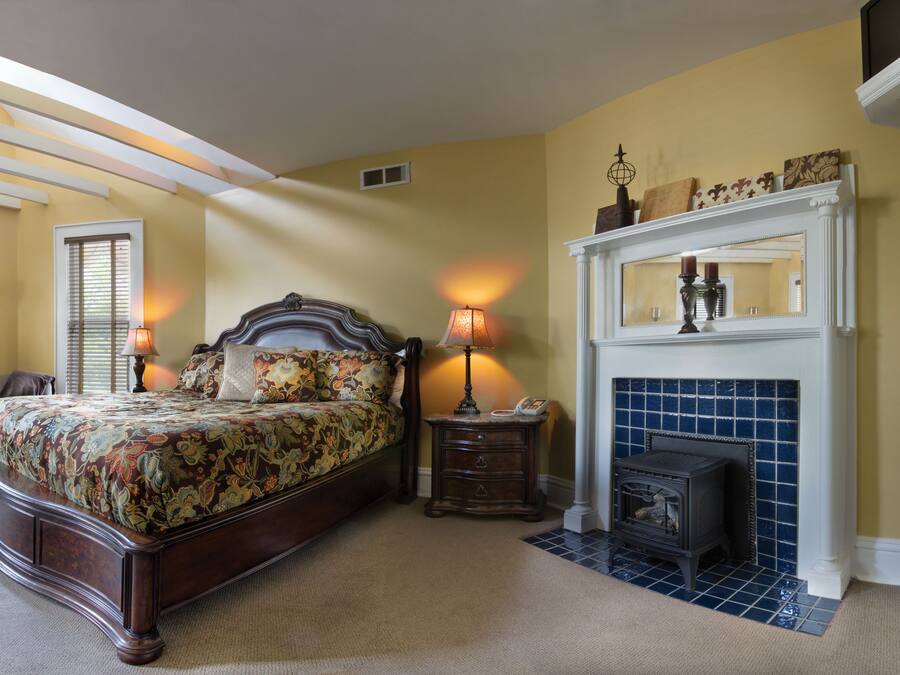 Une chambre à coucher avec un grand lit, une cheminée et un lustre.