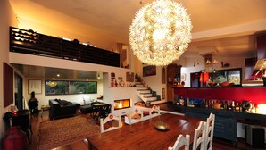 A modern living room with a wooden dining table, a fireplace, and a staircase leading to an upper level. - Eco Suites Resort (Santiago do Cacém)