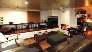 A living room with a fireplace, a television, a sofa, and a coffee table. - Eco Suites Resort (Santiago do Cacém)