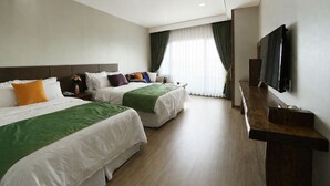 A hotel room with two beds, a TV, and a large window with curtains.