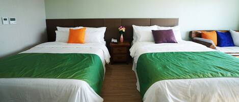 Quarto de hotel com duas camas, cada uma com roupa de cama branca e colchas verdes. Um criado-mudo com um telefone e um vaso de flores fica entre as camas.