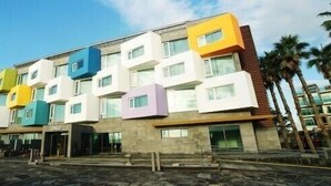 A multi-story building with a modern design, featuring a mix of white, yellow, blue, and purple facades.