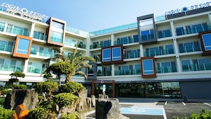 A multi-story building with the sign "Login Resort" indicating it is a hotel. There are multiple balconies with glass railings, and the building has a modern architectural style. - Login Resort (Jeju City)