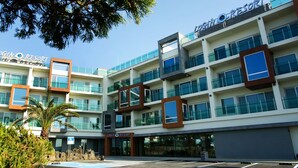 A modern multi-story hotel with a prominent "Login Resort" sign, featuring a mix of glass and concrete architecture, and a parking area in front. - Login Resort (Jeju City)