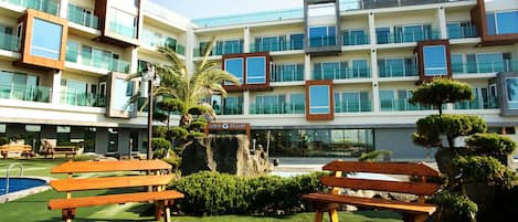 A modern building with multiple balconies, a sign reading "LogIn Resort," and outdoor seating areas.