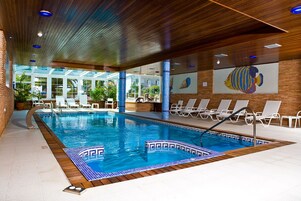 Una piscina techada, una piscina al aire libre de temporada, sombrillas