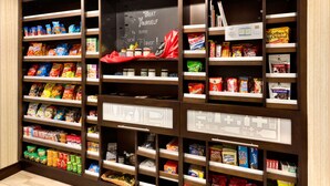 A snack display in a store with various packaged snacks and a chalkboard sign. - Hampton Inn & Suites Monroe (Monroe)