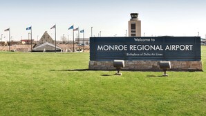A sign welcoming to Monroe Regional Airport, with flags and a control tower in the background. - Hampton Inn & Suites Monroe (Monroe)