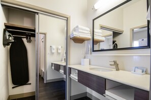 A modern bathroom with a glass shower enclosure, a vanity with a sink and mirror, and a towel rack with folded towels.
