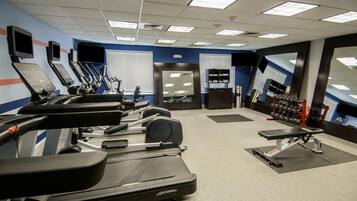 A gym with treadmills, weight machines, and dumbbells.
