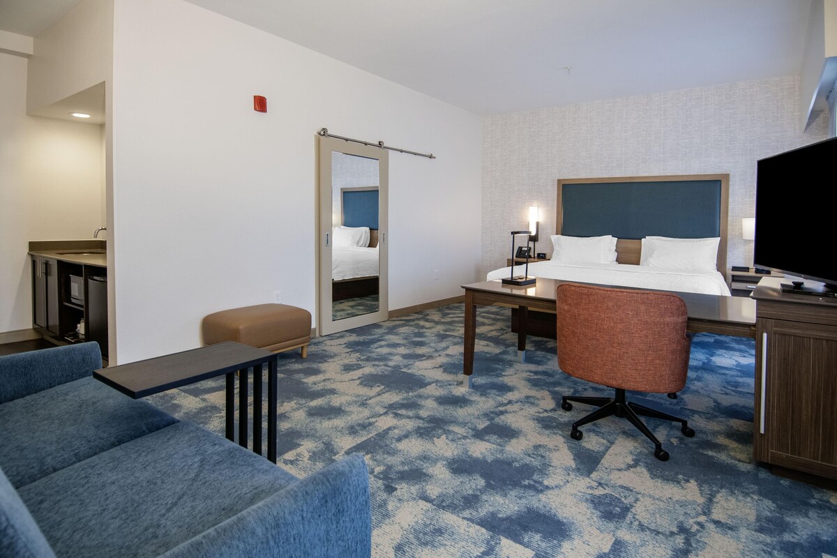 A hotel room with a bed, desk, chair, and a television.