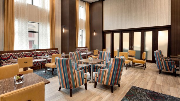 A hotel lobby with striped armchairs, a central coffee table, and a seating area with a patterned sofa. - Hampton Inn & Suites Monroe (Monroe)