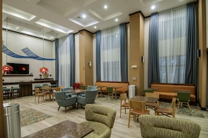 A hotel lobby with seating arrangements, a TV, and a decorative wall.
