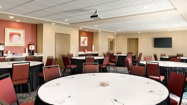 A conference room with multiple tables and chairs, equipped with a projector and a flat-screen TV. - Hampton Inn & Suites Monroe (Monroe)