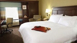 A hotel room with a large bed, a desk, a chair, and a nightstand with a lamp. - Hampton Inn & Suites Monroe (Monroe)
