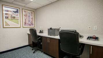 A conference room with a long table, two chairs, a printer, and two framed pictures on the wall.