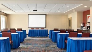 A conference room with rows of tables, chairs, a projector screen, and a carpeted floor. - Hampton Inn & Suites Monroe (Monroe)
