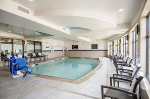 A swimming pool with lounge chairs and a no-lifeguard sign.