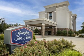 A Hampton Inn & Suites by Hilton building with a clear sky.