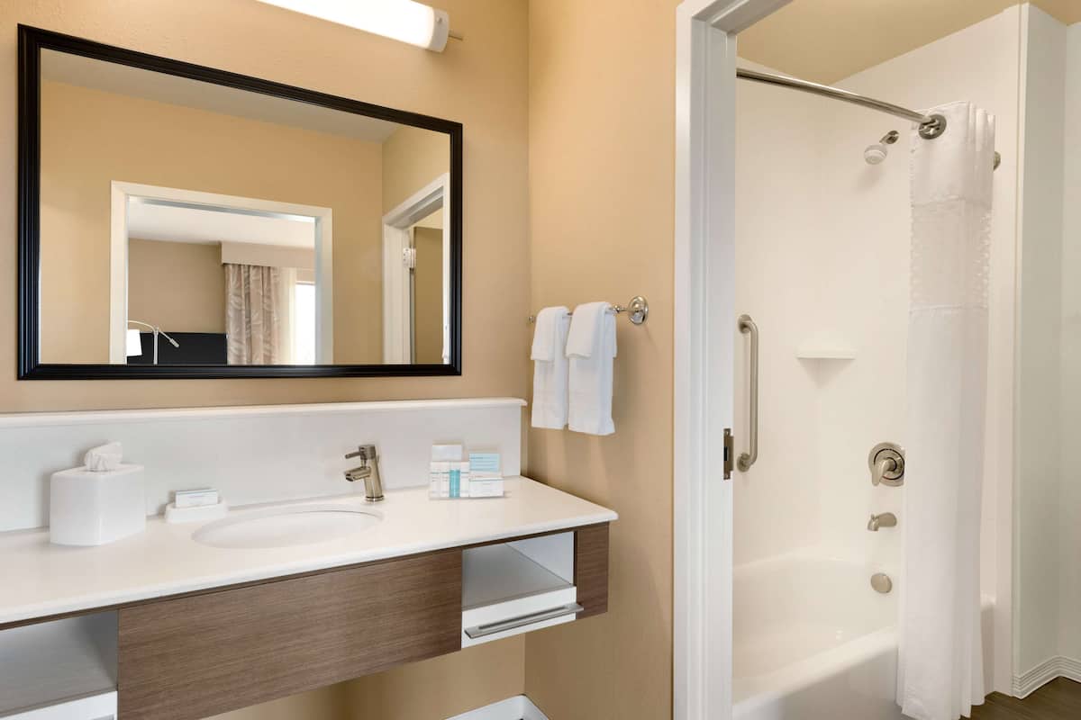 A bathroom with a white sink, mirror, and shower curtain.