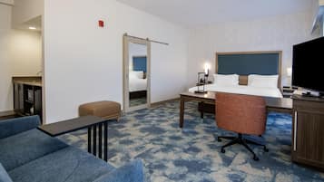 A hotel room with a bed, desk, chair, and a television.