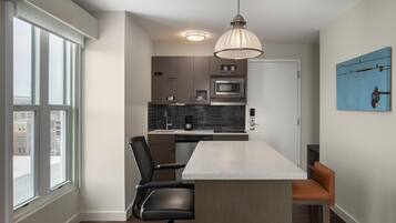 A modern kitchen with a central island, a dining area with chairs, and a large window.