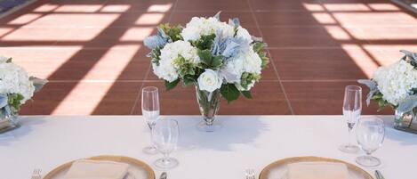 Mesa lista para dos personas con servilletas blancas, platos con borde dorado y copas de cristal.