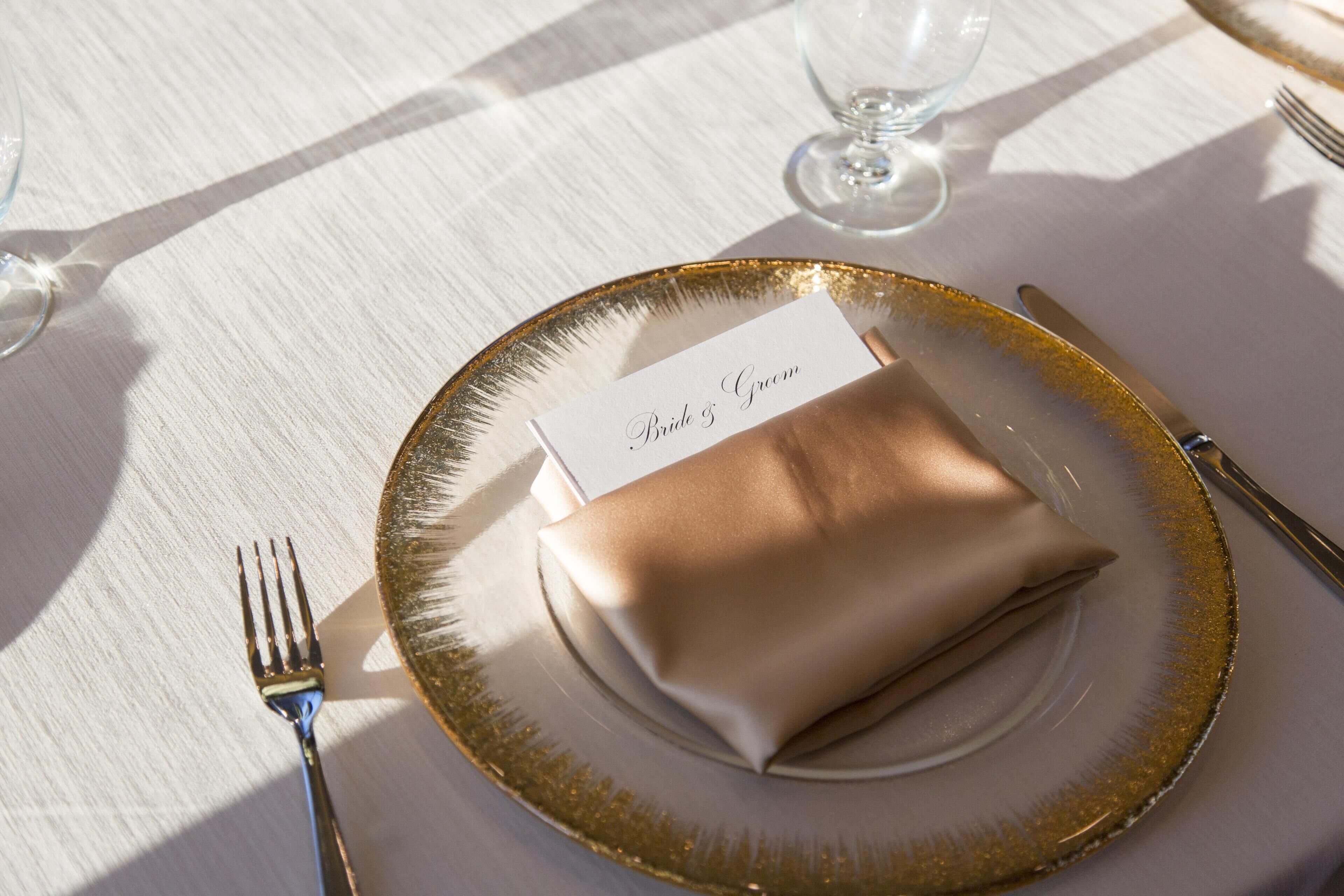 A table setting with a folded napkin, a name card, and a glass of water.
