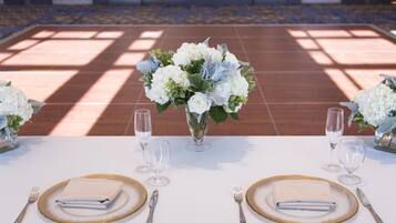 Mesa lista para dos personas con servilletas blancas, platos con borde dorado y copas de cristal.