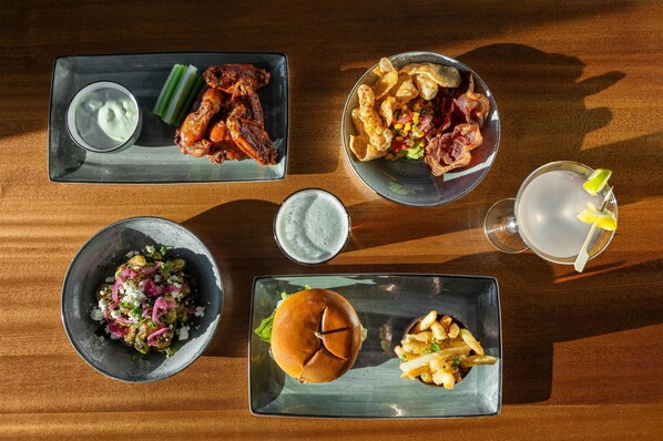 A table with various food items including wings, chips, a burger, and a drink.