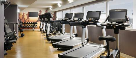 A gym with treadmills, ellipticals, and dumbbells.