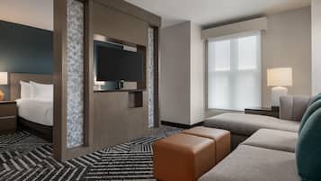 Una habitación de hotel con cama, televisor, sofá y escritorio.