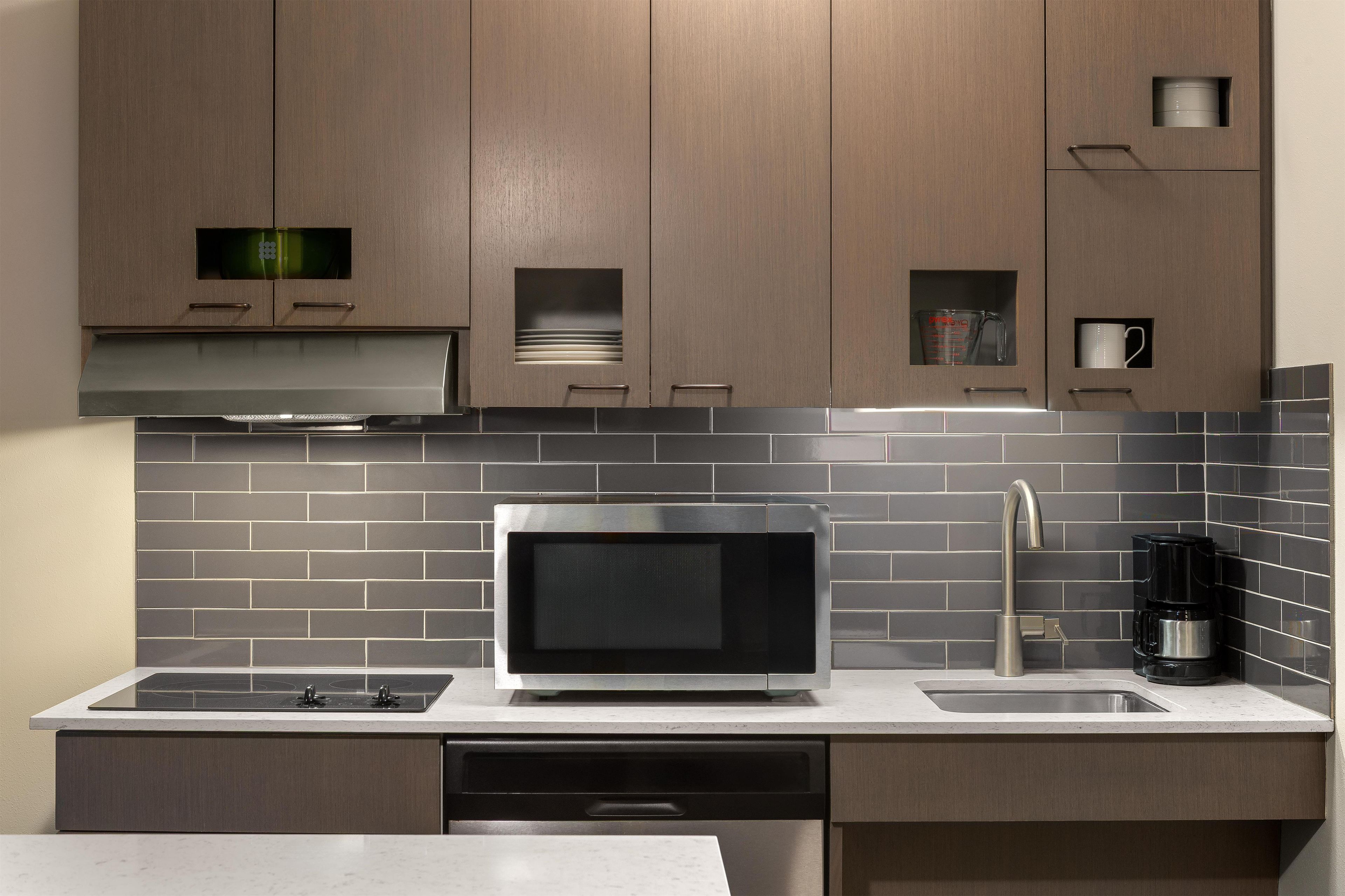 A modern kitchen with a built-in microwave, a coffee maker, and a dishwasher.