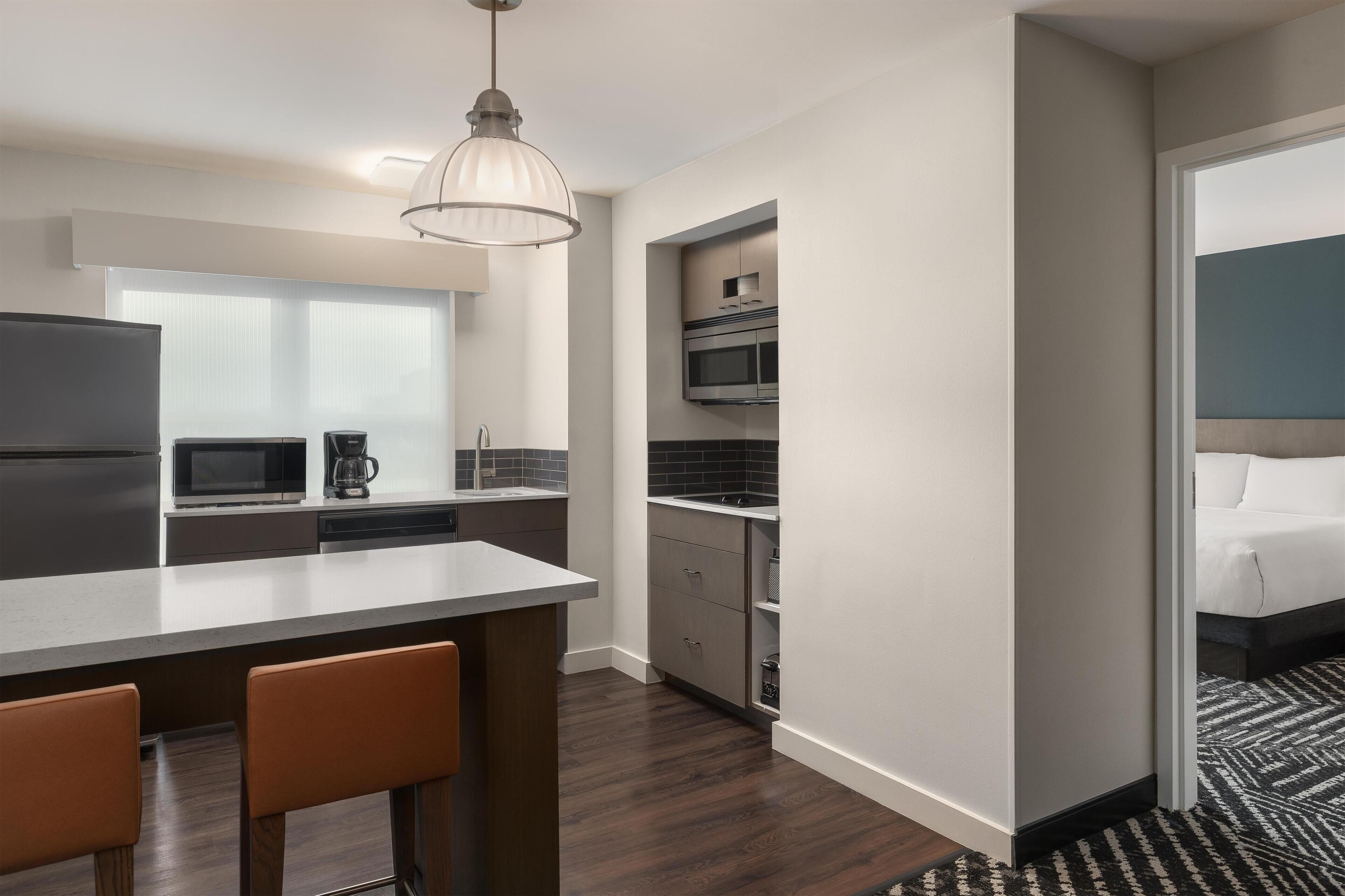 Una cocina moderna con una isla central, microondas, cafetera y horno empotrado.