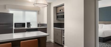 Una cocina moderna con una isla central, microondas, cafetera y horno empotrado.