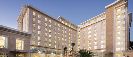 A multi-story hotel with a central courtyard, a covered entrance, and a brick facade.
