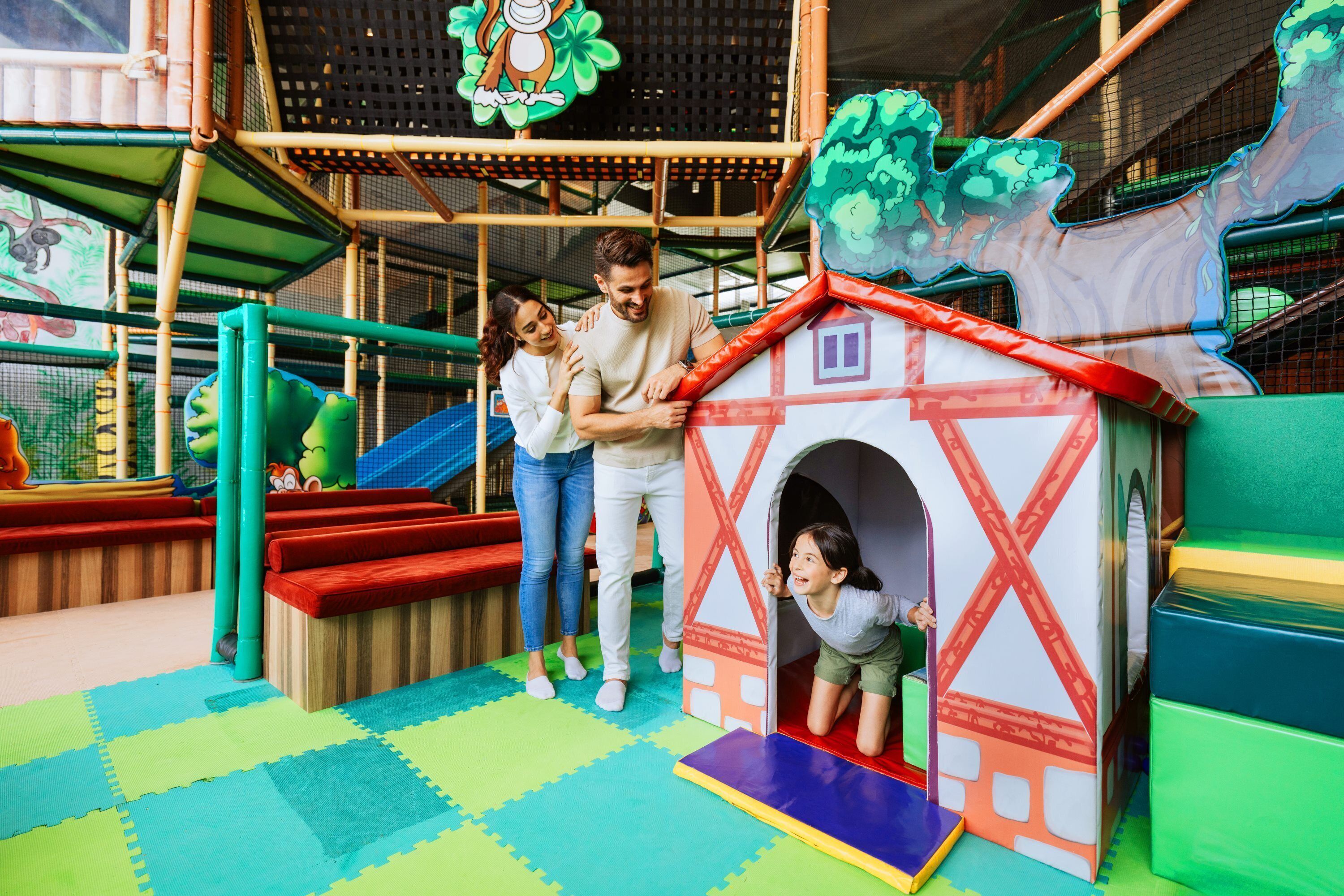 A play area with a climbing structure, a slide, and a small house playhouse.