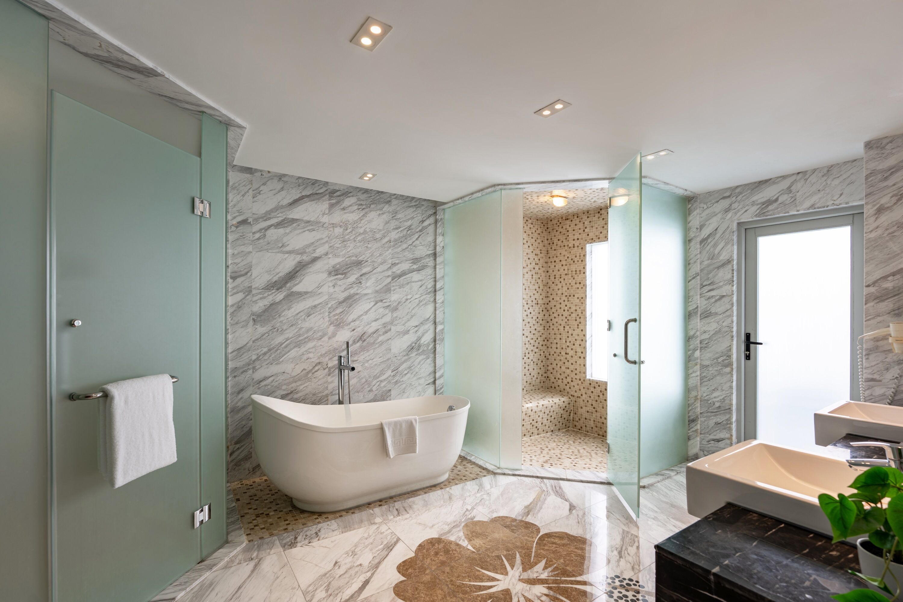 A modern bathroom with a freestanding bathtub, a glass-enclosed shower, and a separate sink area.