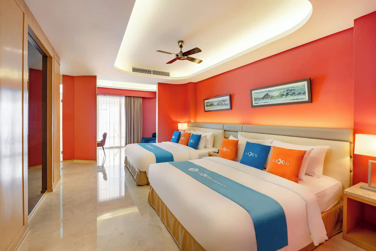 A hotel room with two beds, a ceiling fan, and a large window.