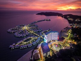 A waterfront hotel with a distinctive star-shaped pier, a large building with a prominent digital display, and a well-lit beachfront.