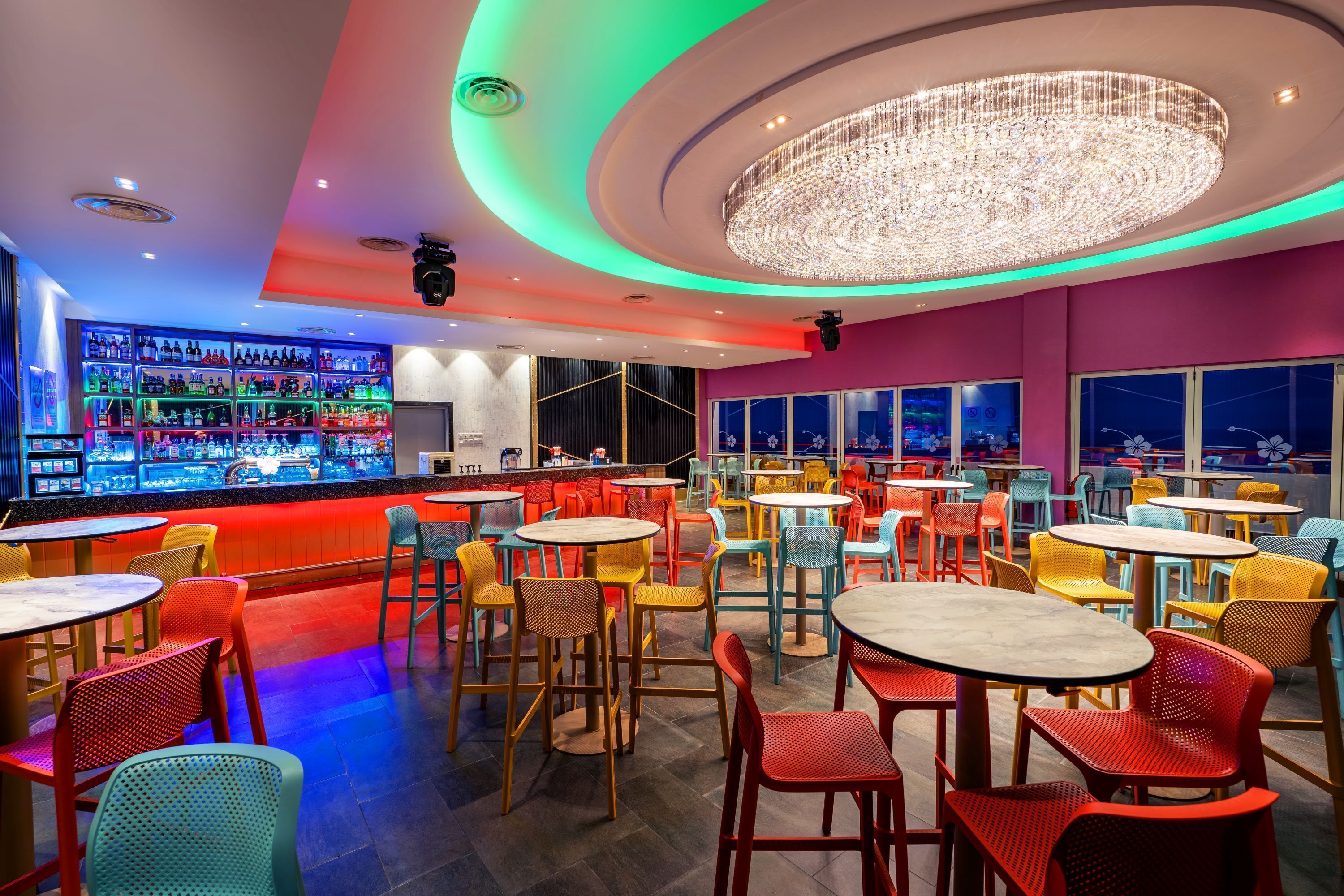 A bar area with a variety of seating options and a large, illuminated chandelier.
