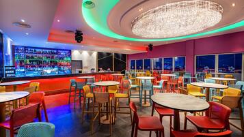 A bar area with a variety of seating options and a large, illuminated chandelier.