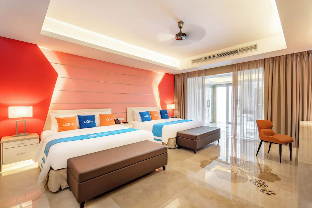 A modern hotel room with two beds, a seating area, and a large window with curtains.