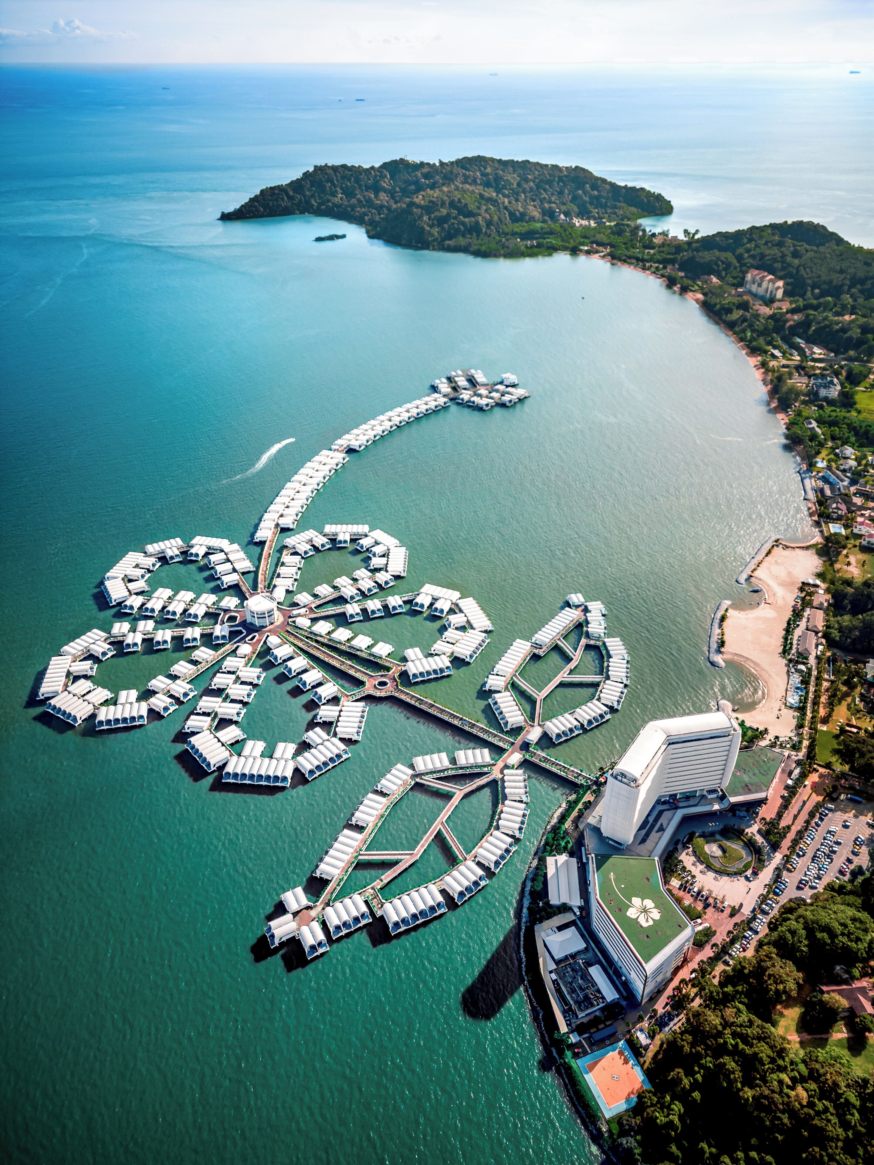 An aerial view of a marina with multiple docks and a large building with a distinctive roof design.