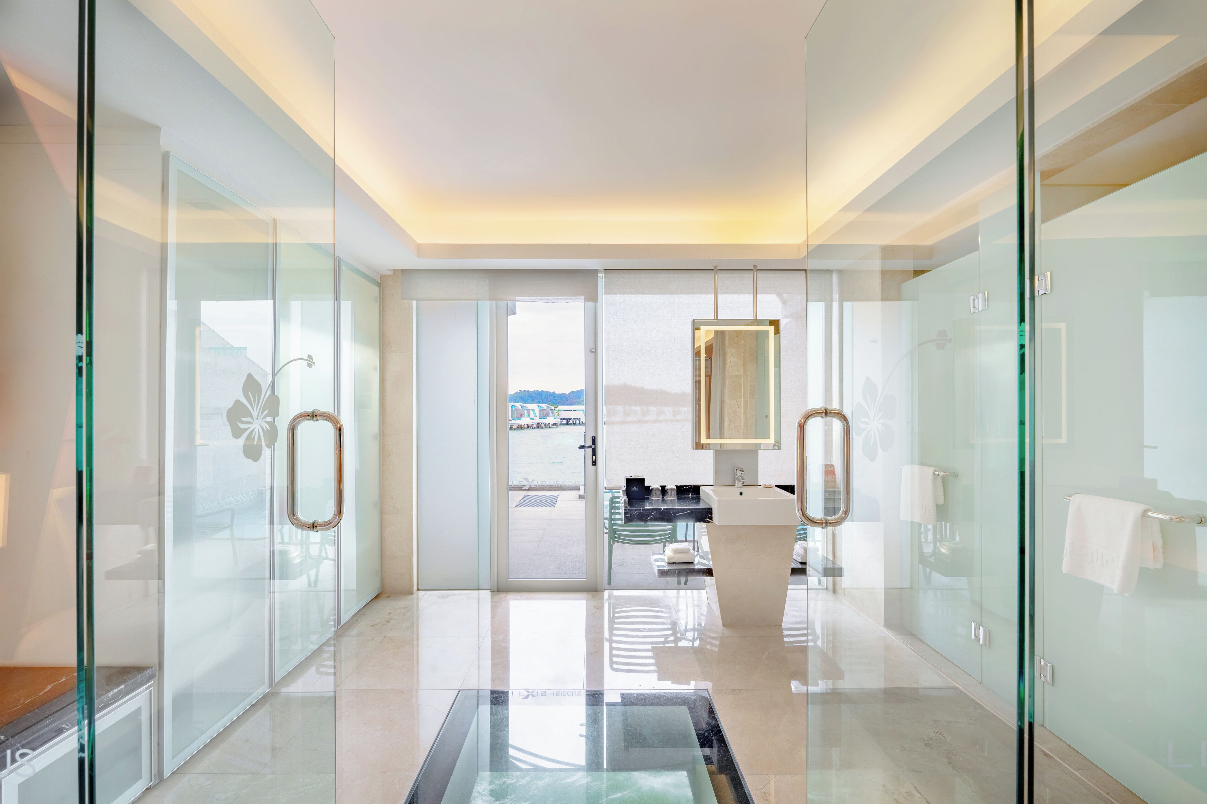 Una hall moderna di un hotel con un divisorio in vetro, una reception e vista sull'esterno.