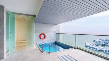 Un área de piscina interior moderna con paredes de vidrio transparente, suelo de baldosas y un flotador en la pared.