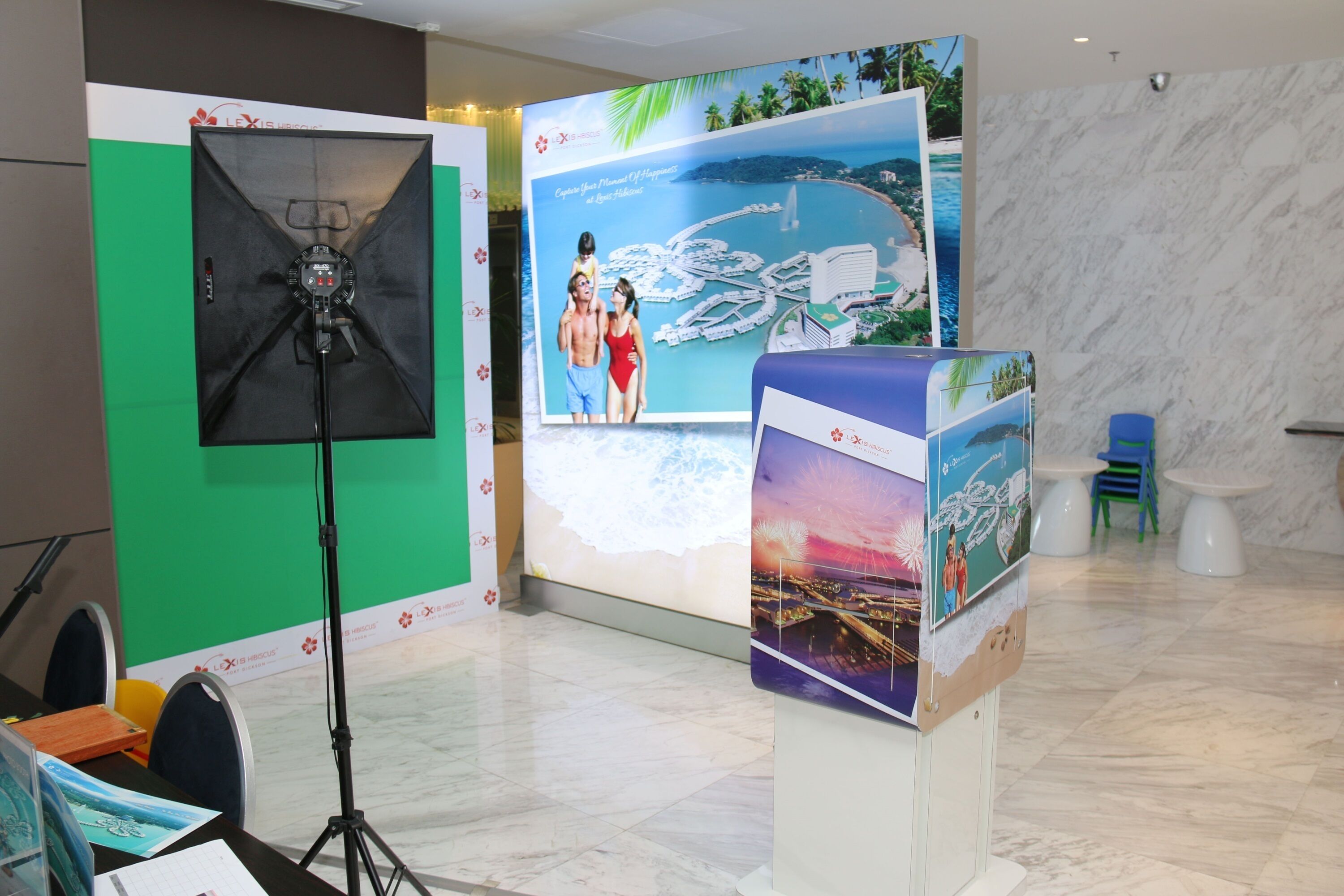 Un salón de conferencias con una pantalla verde, una pantalla de proyección y una mesa blanca con sillas.