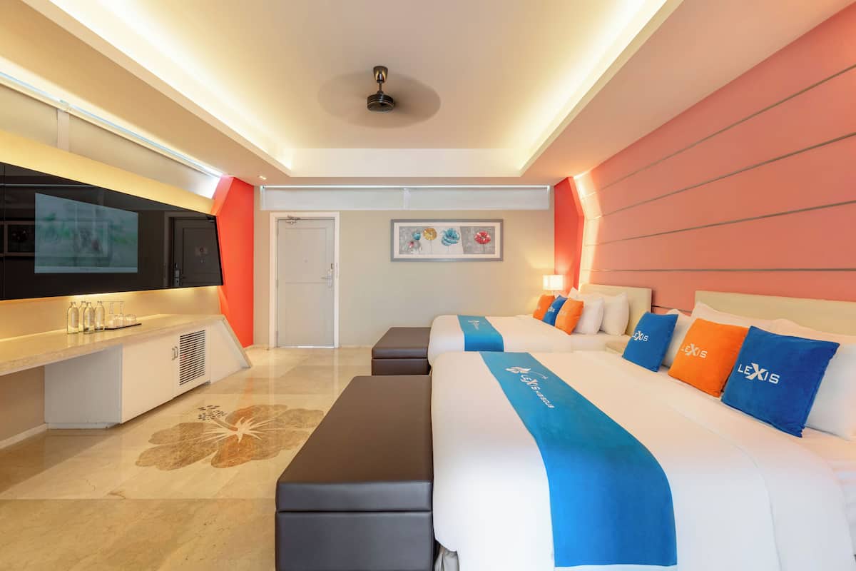 A modern hotel room with a large bed, a desk with a flat-screen TV, and a seating area.